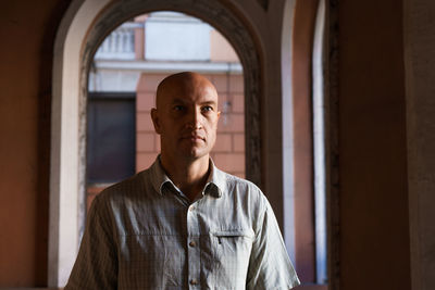 Bald middle-aged man smiling happy walking in the city against the background