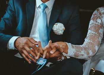 Midsection of bride and bridegroom holding hands during wedding ceremony