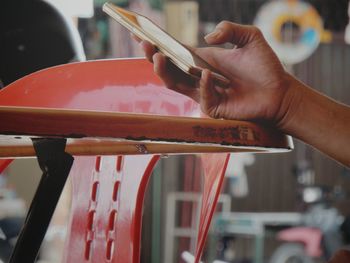 Cropped hand of woman using mobile phone at table