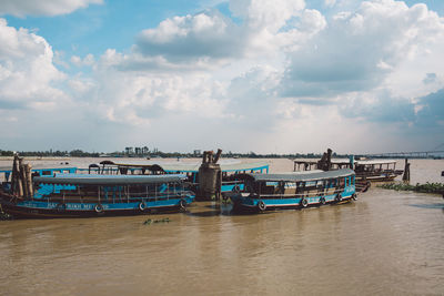 Fishing boats moored at harbor against sky