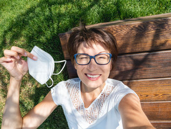 Woman takes off protective mask to make selfie on smartphone. new normal. coronavirus covid19.