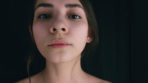 Close-up portrait of woman against black background