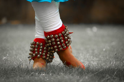 Low section of woman wearing anklets standing on land