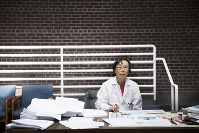 Portrait of senior female scientist sitting at desk with documents