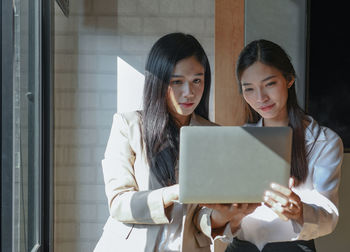 Young woman using smart phone in laptop