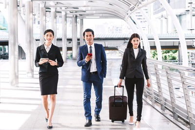 Full length of colleagues walking on bridge in city