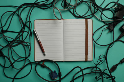 Directly above of opened book with cables against green background