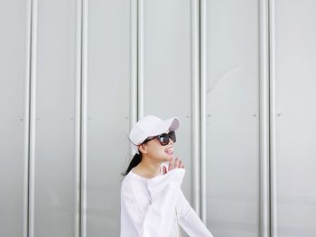 Smiling woman standing against white wall