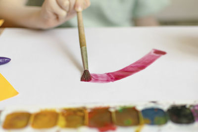 Cropped hand of boy painting at classroom