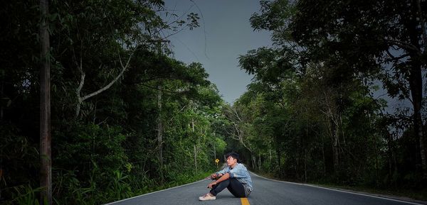 Side view of man on road amidst trees