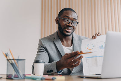 Portrait of young man using laptop at office