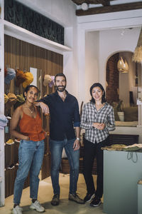 Portrait of multiracial male and female sales colleagues standing together at fashion store