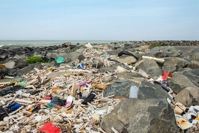 Garbage on rock by sea against sky