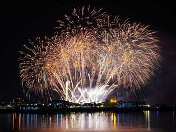 Firework display over river against sky at night