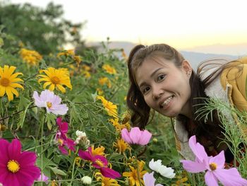 Portrait of smiling young woman with yellow flowering plants on field