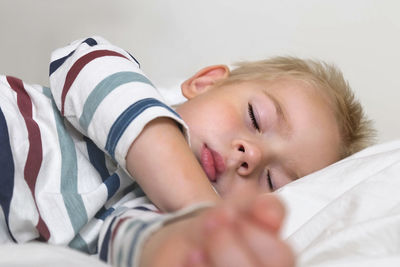 Young child sleeping on white smooth blanket. little 3 years old kids sleeps alone in cozy bedroom