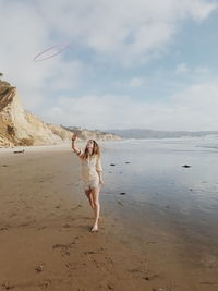 Woman standing on beach against sky