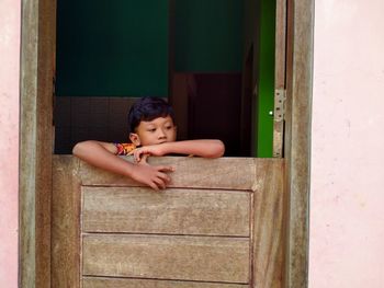 Portrait of boy looking through open door