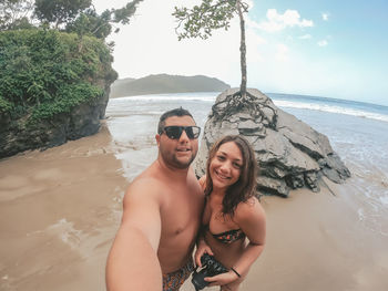 Portrait of smiling couple standing at beach