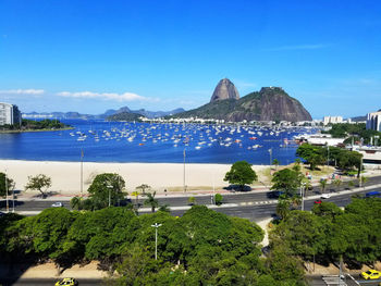 High angle view of city by sea against blue sky