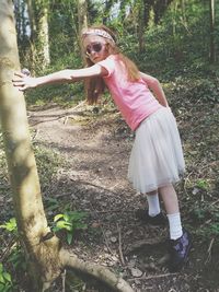 Woman standing by tree on field in forest