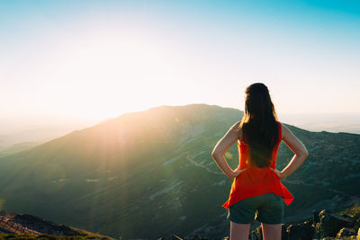 Rear view of woman looking at mountains against sky