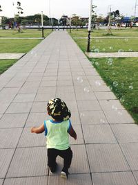 Rear view of toddler boy walking on footpath at park