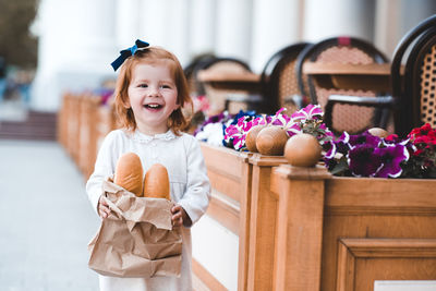 Cute smiling girl holding loaf of bread