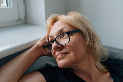 Mature woman looking away sitting by window