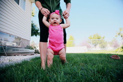 Portrait of baby girl with mother standing on grassy field