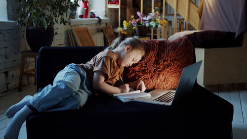 Side view of girl doing homework at home