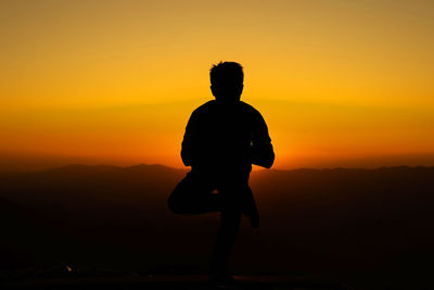 Silhouette man standing against orange sky