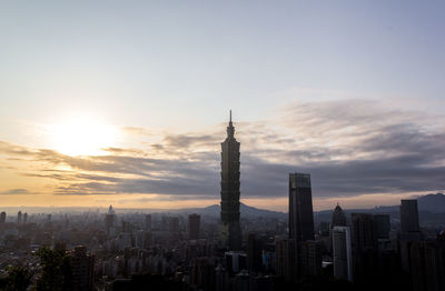 Modern buildings in city against sky during sunset