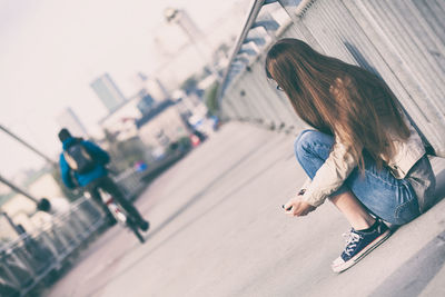 Side view of a woman sitting by the road