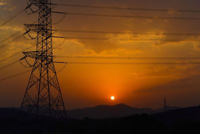 Silhouette electricity pylon against sky during sunset