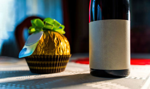 Close up of a red wine bottle with black white label for mock up with a big round wrapped chocolate