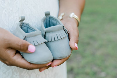 Midsection of pregnant woman holding shoes