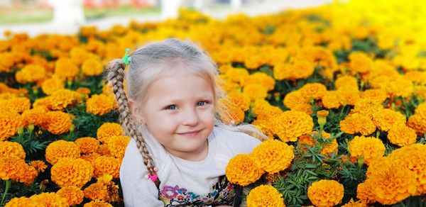 Portrait of cute girl standing on yellow flowering plants