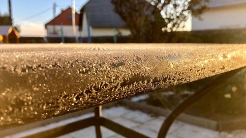 Close-up of railing by house on field against sky