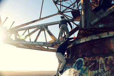 Low angle view of men climbing on abandoned building