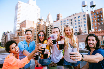 Portrait of people holding drinks against building