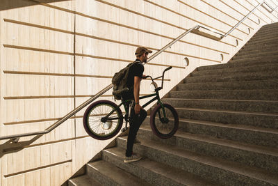 Man moving up with bicycle on staircase