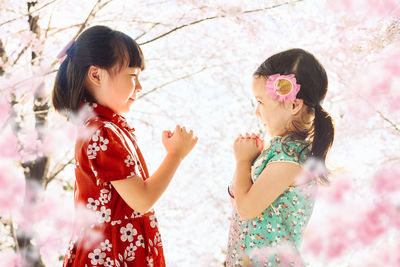 Playful siblings standing against tree