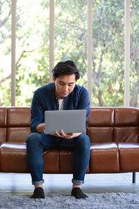 Young man using mobile phone while sitting on sofa
