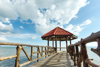 Wooden jetty on pier at beach against sky