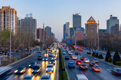 Traffic on city street by buildings against sky