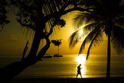 Silhouette people standing on beach against sky during sunset