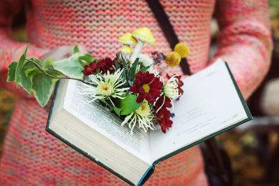 Colored flower arrangement in a vintage book in the hands of a model