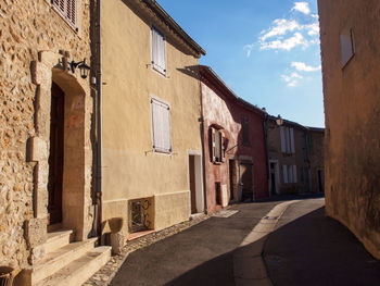 Empty alley amidst buildings in town against sky