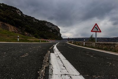 Road signs by mountain against sky
